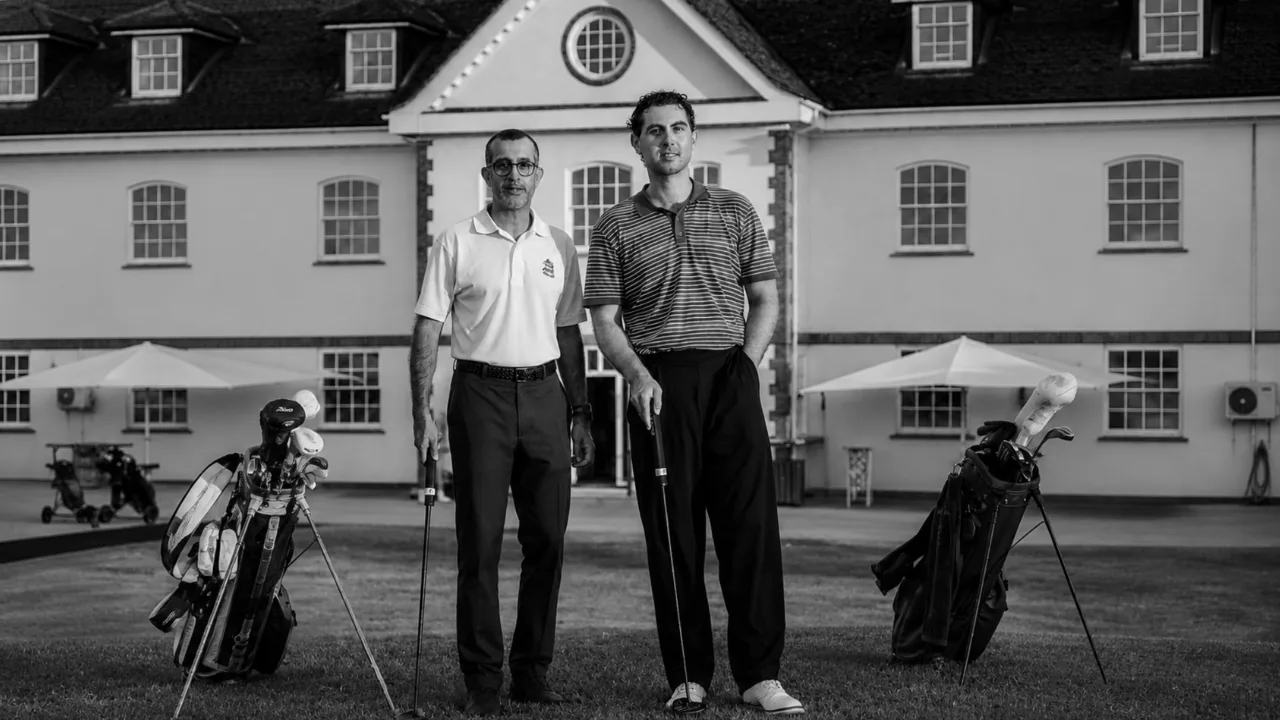 Zaheer Merali and Jarrad Hicks outside a clubhouse, with golf bags beside them.